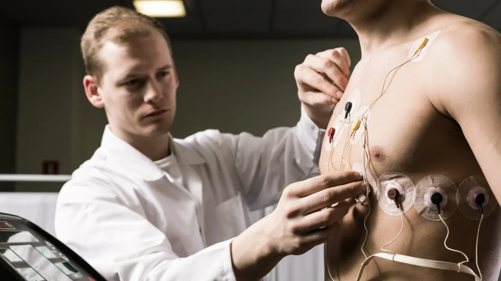 Médecin du sport posant des électrodes ECG sur le torse d'un athlète